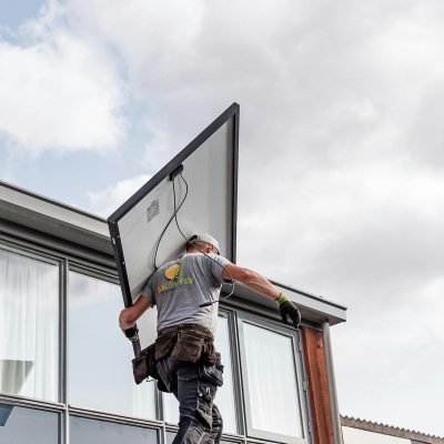 Photo by Stefan de Vries A worker installs a solar panel on a residential rooftop emphasizing renewable energy.