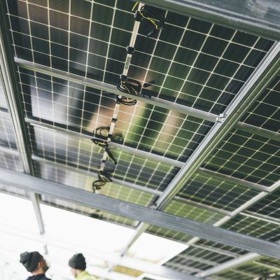 Close-up of solar panels being installed outdoors with technicians visible.